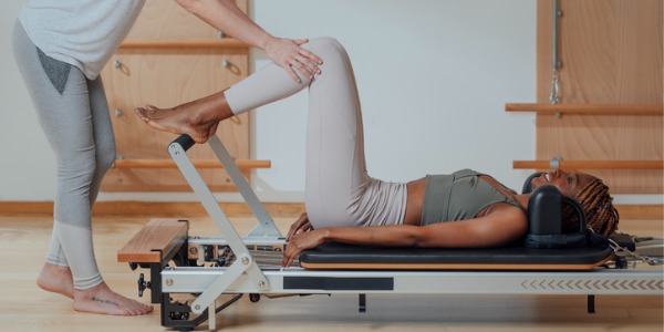 A Pilates instructor helping a client with an exercise.