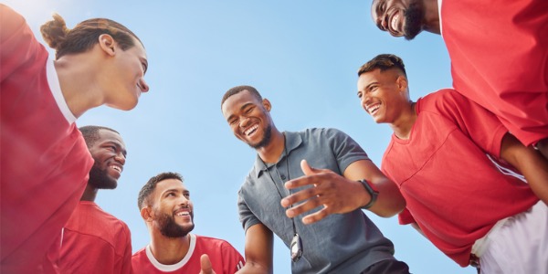 A sports trainer giving athletes some encouraging words on the field.