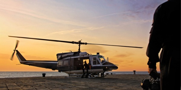 A military air crew officer looking at a helicopter aboard an aircraft carrier.