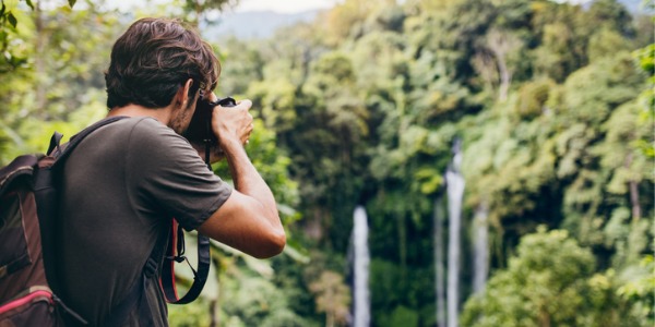 A landscape photographer taking a photograph of a waterfall.