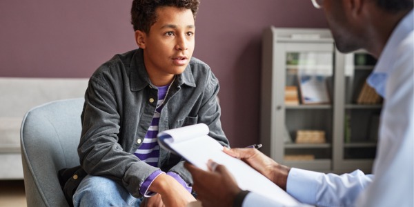 A young boy talking to a child and adolescent counselor.