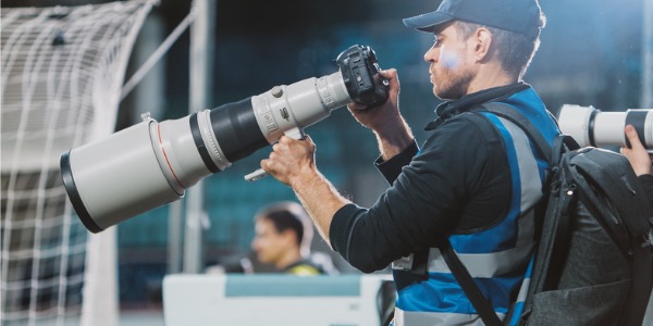 A sports photographer setting up his camera before a soccer game.