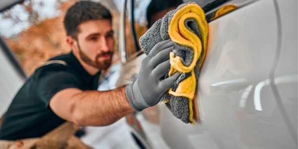 A vehicle cleaner polishing the outside of a car.
