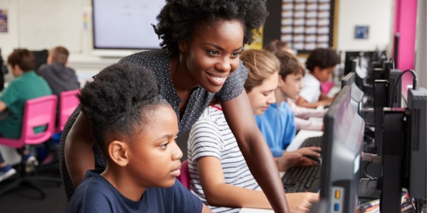 A STEM teacher helping a student with computer work.