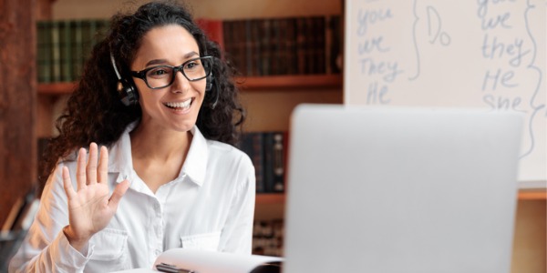 A virtual teacher waving to her online class.