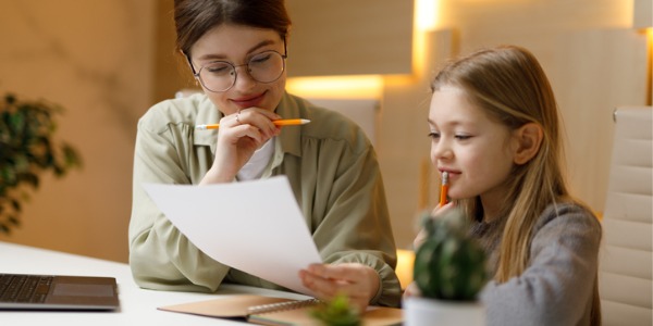 A private tutor helping a young girl with her homework assignment.