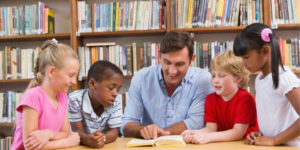 A youth services librarian reading from a book to young library patrons.