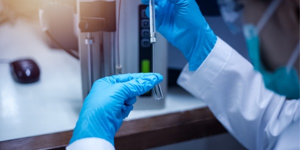 A nanotechnology engineer injecting sample with micro syringe to TOF Mass Spectrometer for analysis in laboratory.