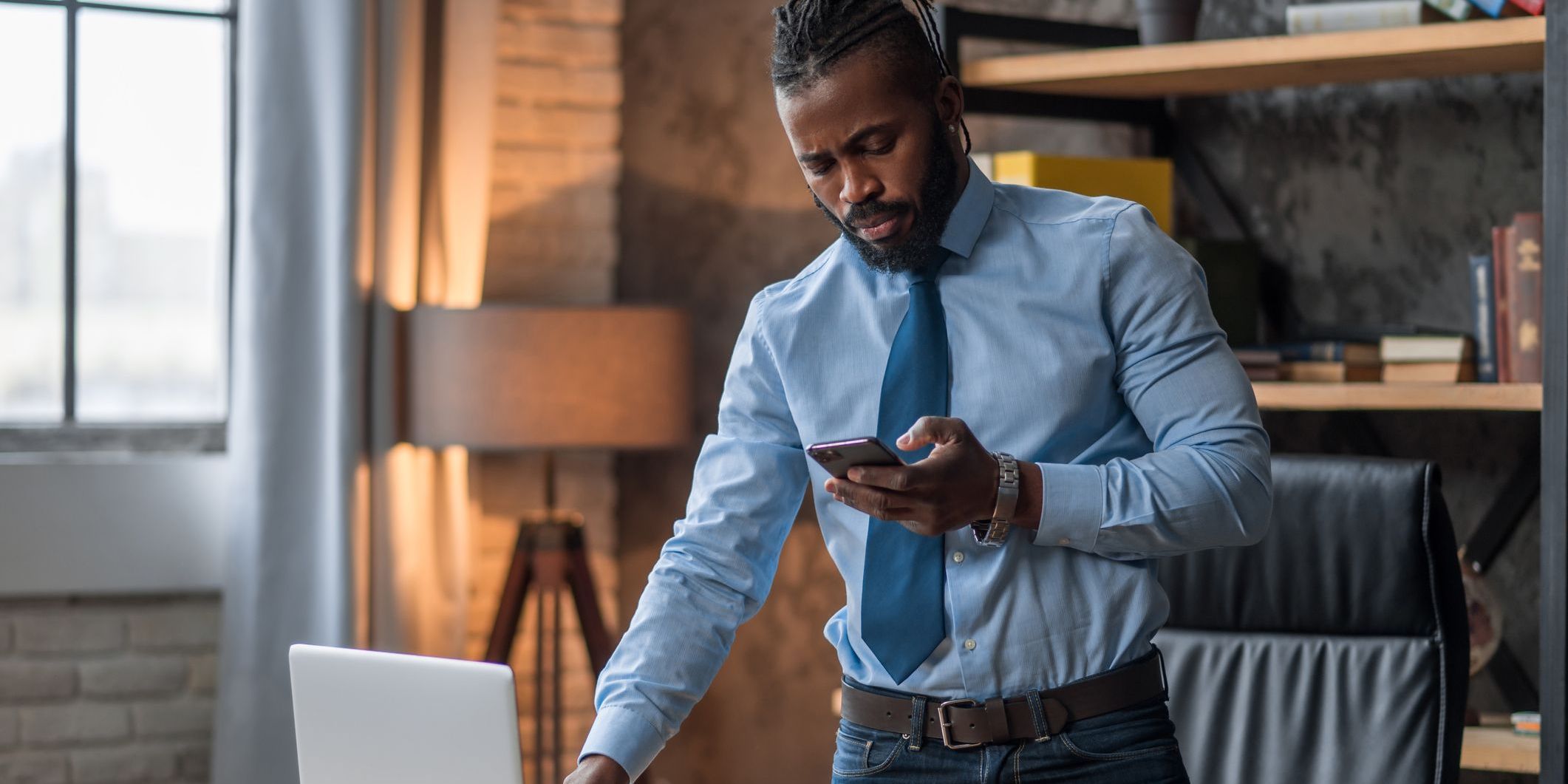 A music business manager working at his desk and looking at his phone.