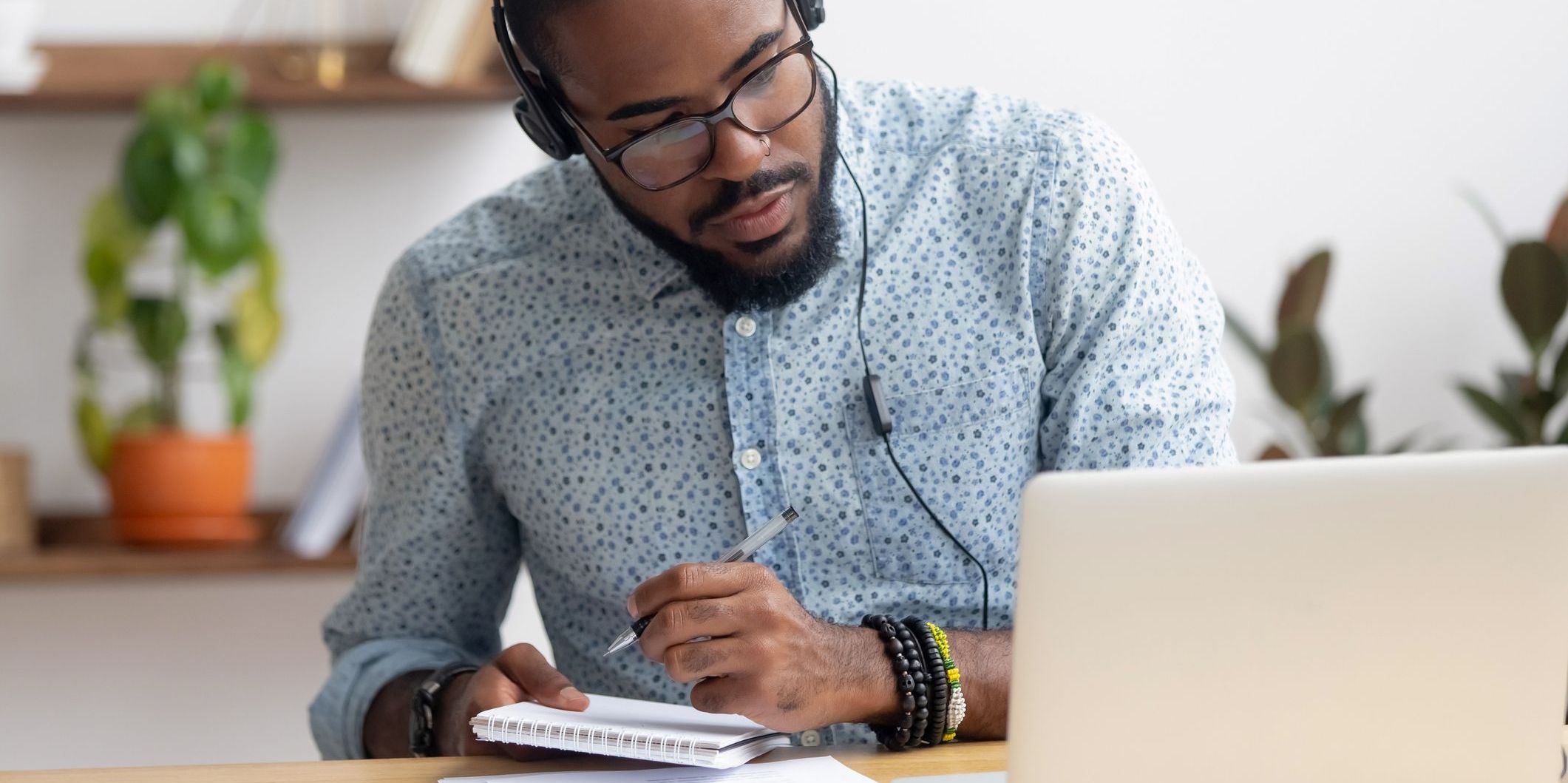 A music supervisor sitting at his desk with headphones on, working on his computer.
