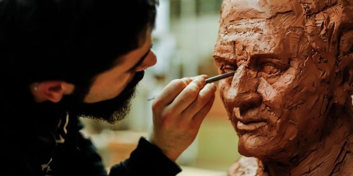 A sculptor molding a face out of clay.