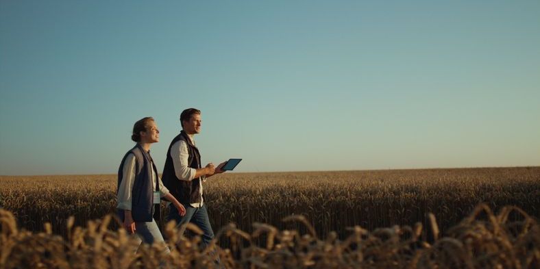 A farm manager talking to a farmer outside in the field.