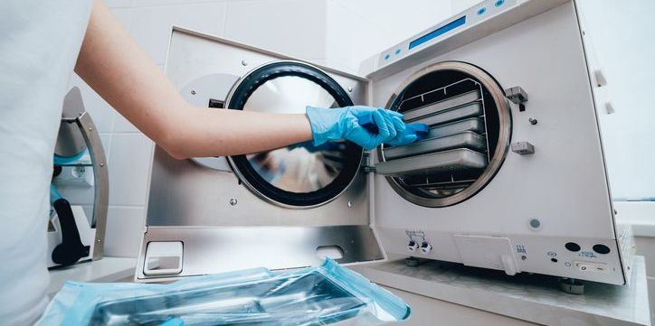 A sterile processing technician using an autoclave to sterilize medical instruments.