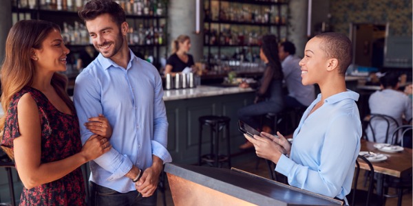 A maitre d' welcoming customers into a restaurant.