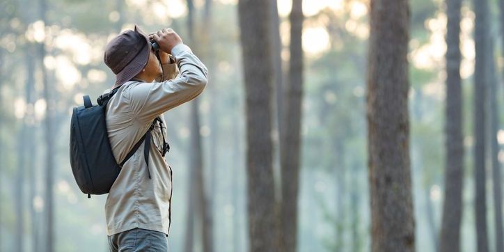 An ornithologist studying birds out in the field.