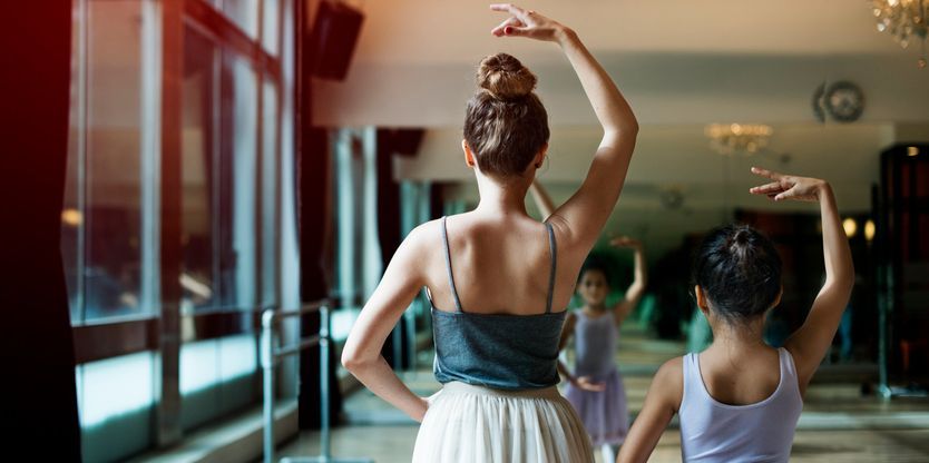 A dance teacher helping a young student.