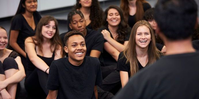 A dance education choreographer at a performing arts school talking to students.