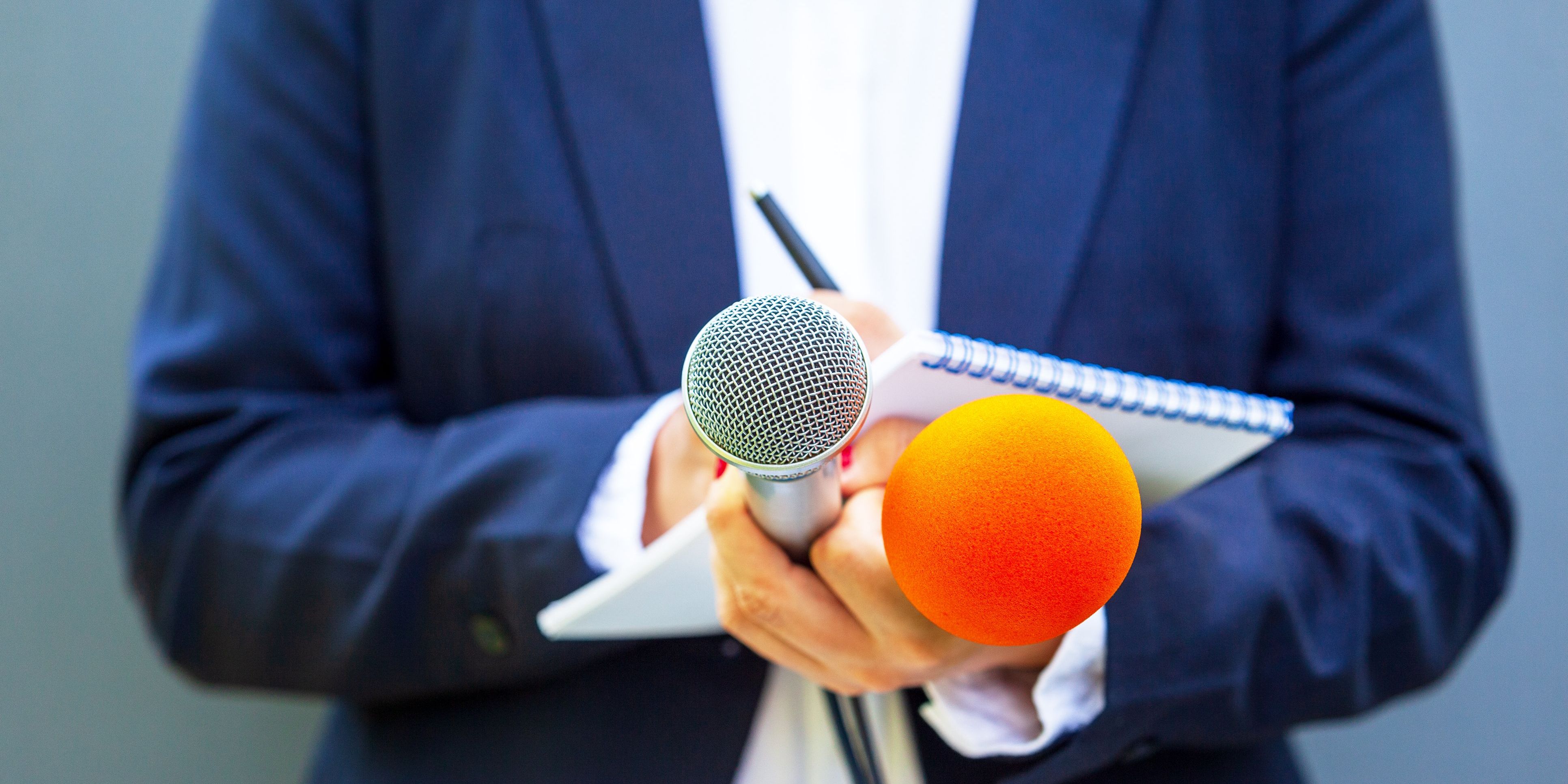A broadcast journalist writing down notes before an interview.