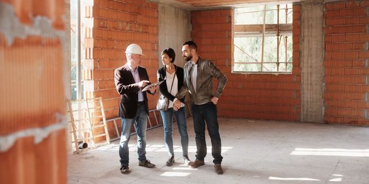 A new construction real estate agent showing a couple a house that is still in construction.