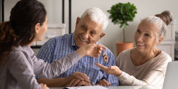 A seniors real estate specialist handing over house keys to her senior clients.