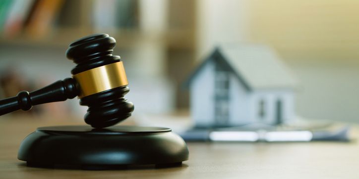 An image of a gavel with a house in the background, depicting a real estate auctioneer.