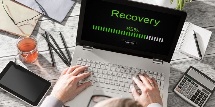 Data recovery concept of hands typing on computer and retrieving lost files.