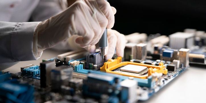 A hardware technician holding a screwdriver and attaching the cooler to the motherboard.