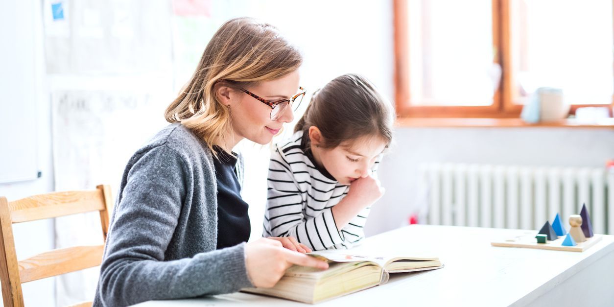 A learning disabilities teacher working with a young student in the classroom.