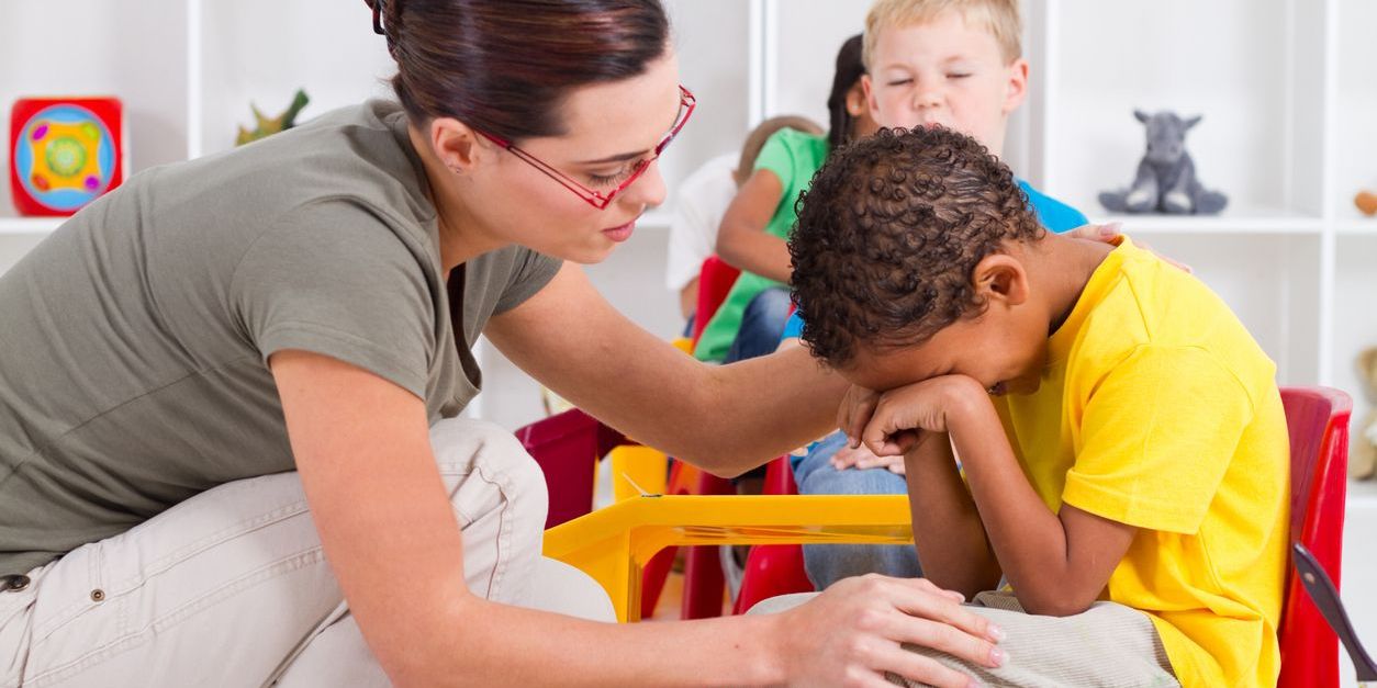 An EBD (emotional and behavioral disorders teacher comforting a crying boy in a classroom.