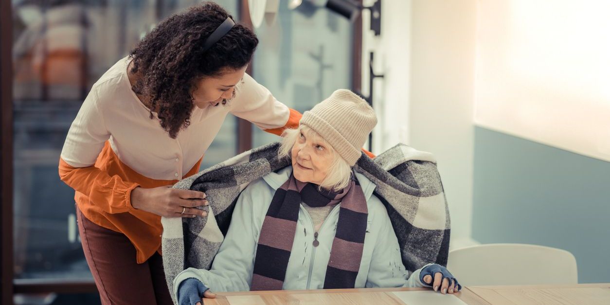 A community social worker reaching out to an elderly woman at a shelter.