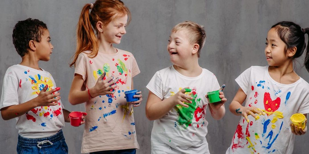 Picture of four happy kids (one with Down syndrome) with finger colours and painted t-shirts.