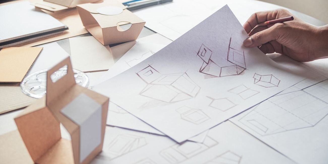 A packaging designer sketching a drawing design mockup of a box and label.