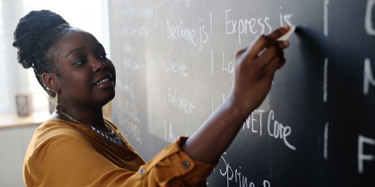 An ELA teacher writing on the blackboard.