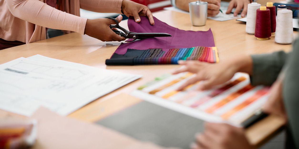 A textile designer cutting a swatch of fabric.