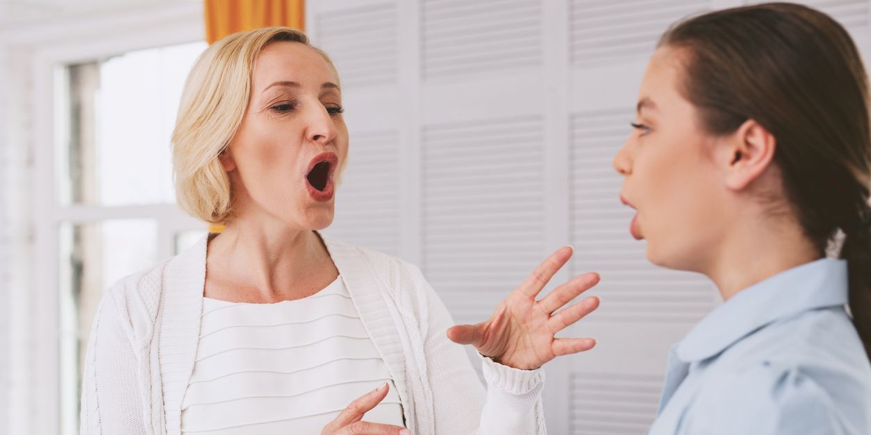 A voice therapist showing a female patient some voice exercises.