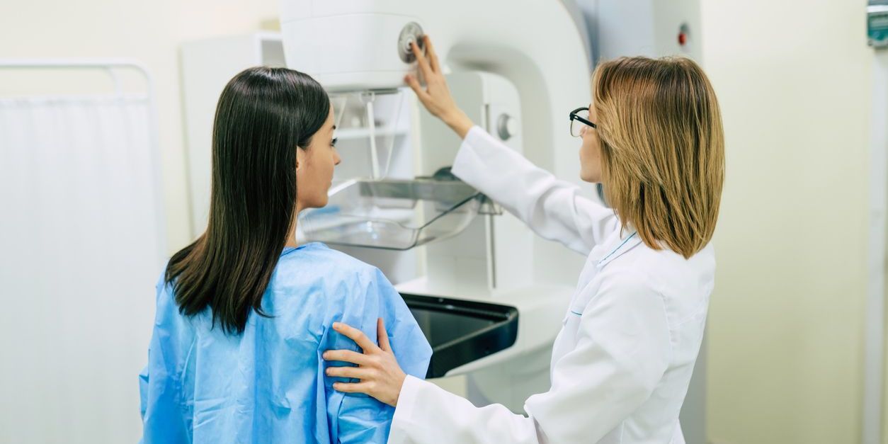 A mammography technician helping a patient with her mammogram.