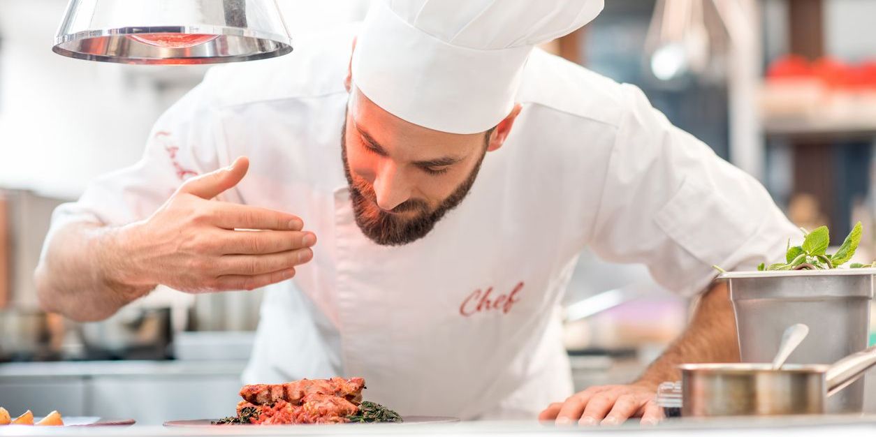 An executive chef checking on the food before it's sent out to the table.