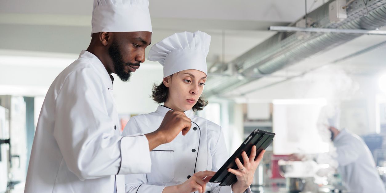 A sous chef talking to another chef in the kitchen.