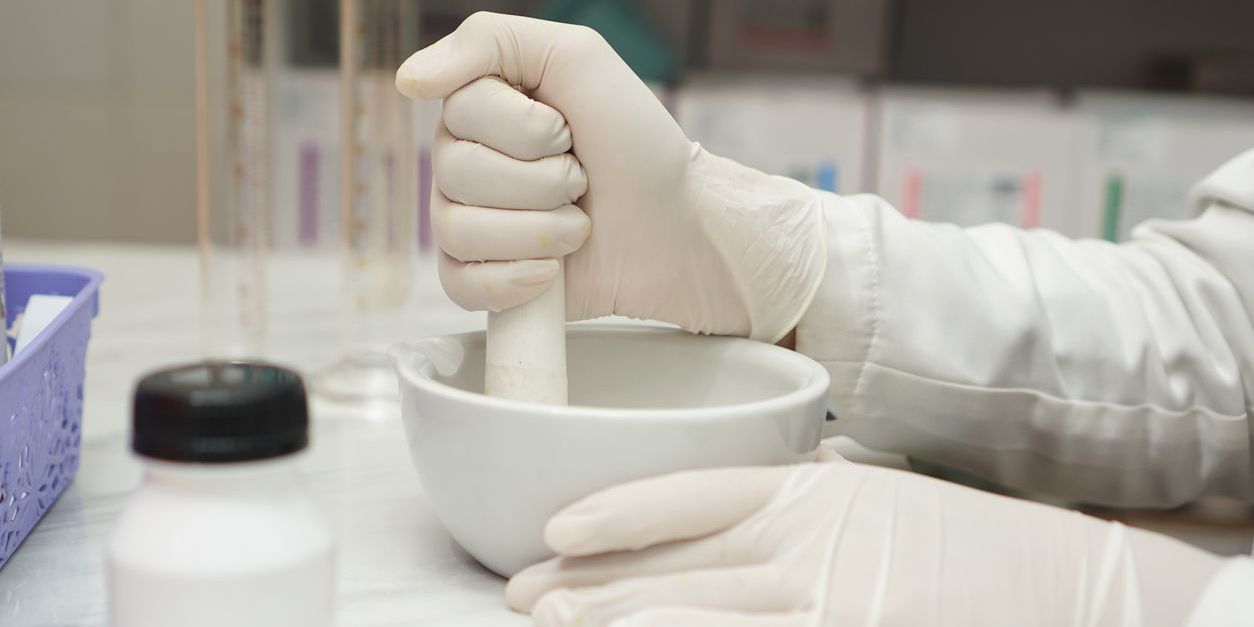 A compounding pharmacist making a custom medication.