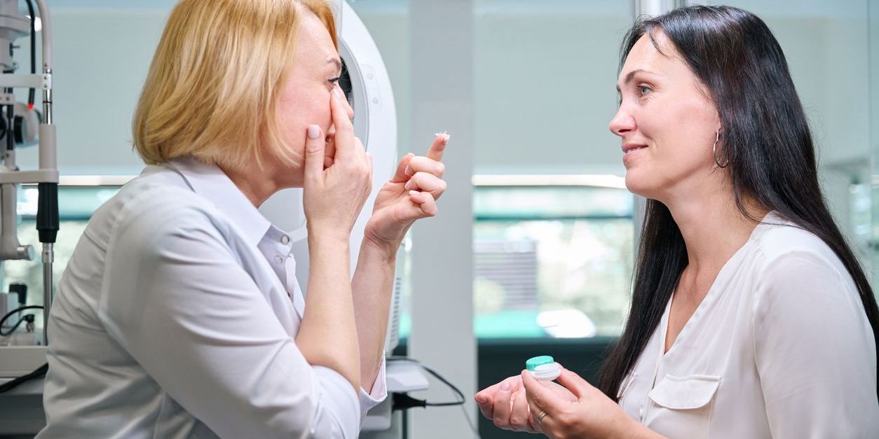 A contact lens specialist helping a patient with her contact lenses.