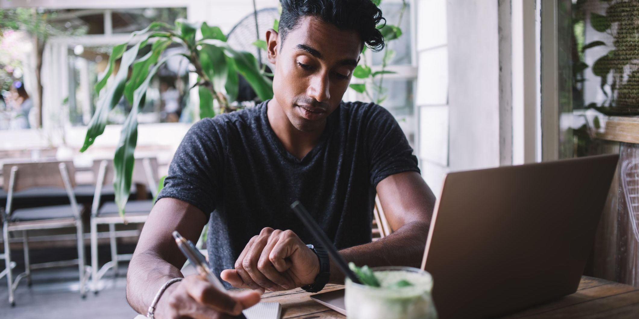 A male working at his desk and checking his watch, aware of time management.