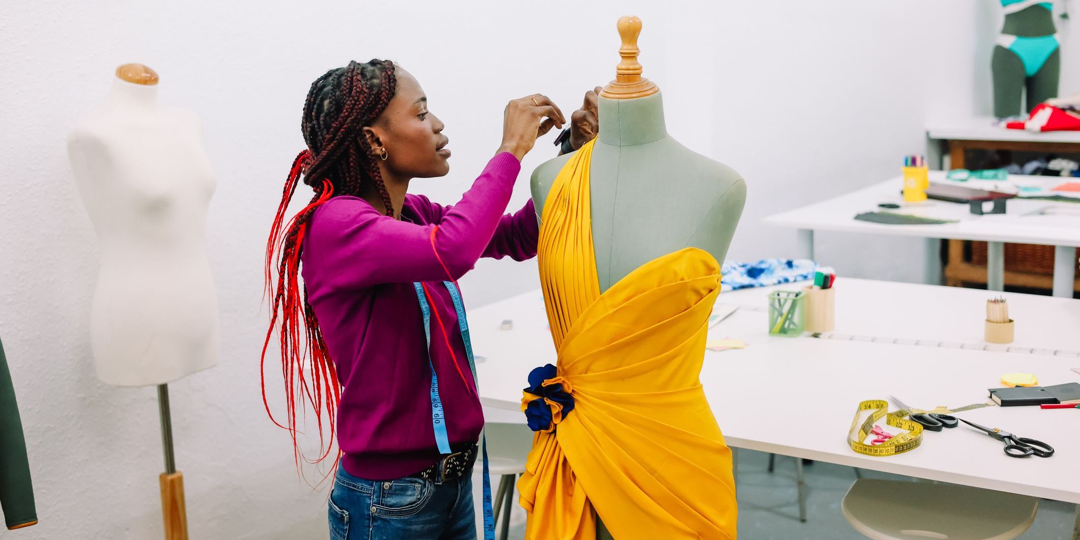 A fashion seamstress pinning a dress onto a dress form.