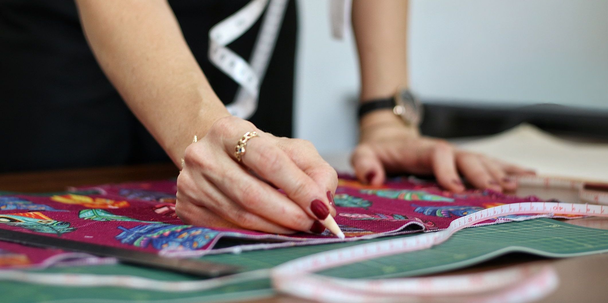 A home decor seamstress marking fabric with chalk on a worktable.