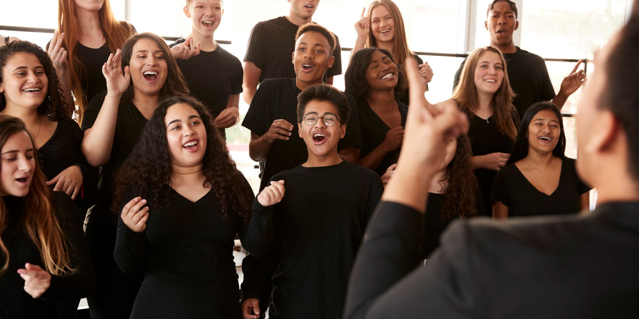 A choral conductor guiding singers through tempo, rhythm, and phrasing.