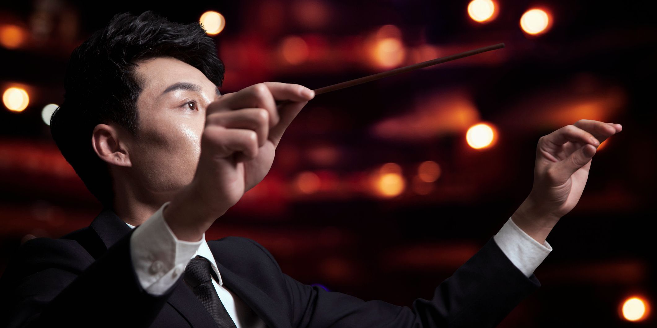 A musical theater conductor leading an orchestra during a performance.