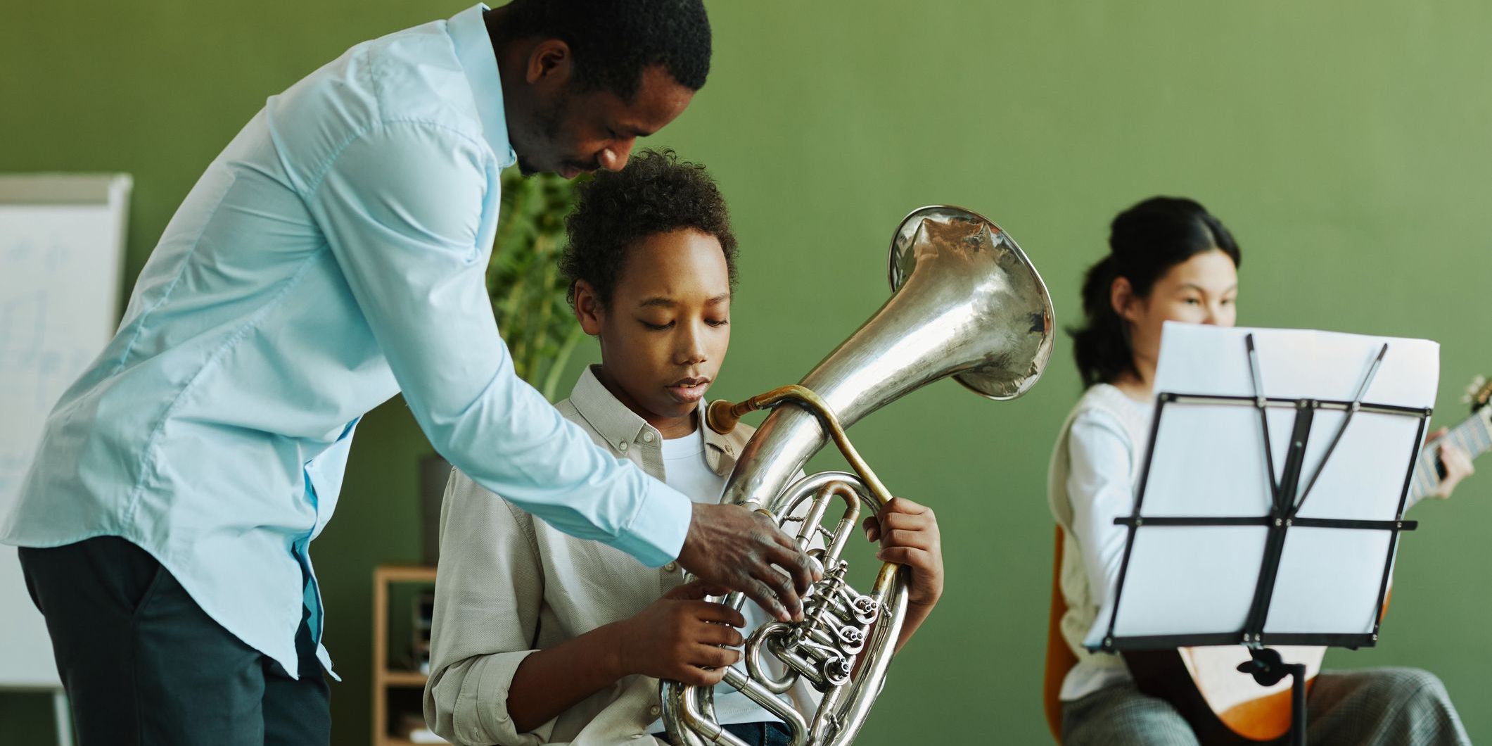 An instrumental music teacher helping a student with the trumpet.