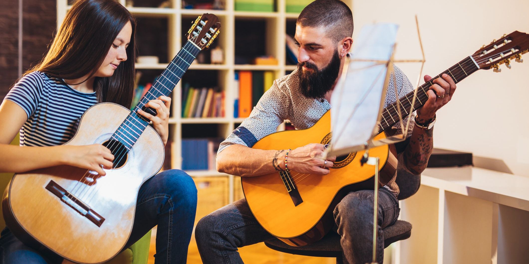 A private music instructor teaching a student how to play the guitar.