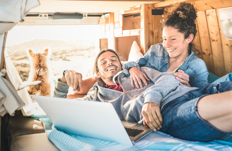 A photo of two travel bloggers and their dog in a custom camper van.