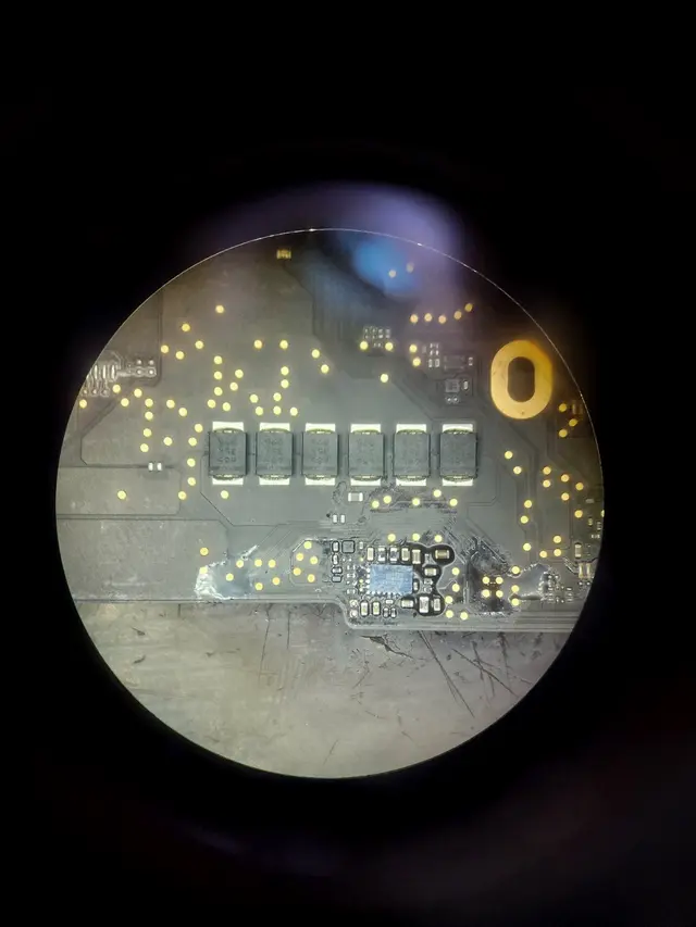 Penggantian IC bus regulator pada logicboard MacBook di bawah mikroskop