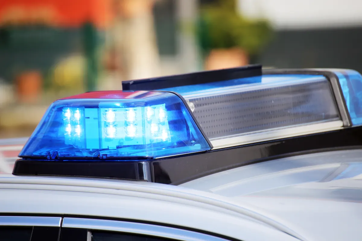 Das Bild zeigt eine Nahaufnahme eines blauen Blaulichts auf dem Dach eines Polizeifahrzeugs, das eingeschaltet ist.